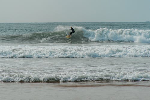 A Person Surfing on Big Waves near the Shore 