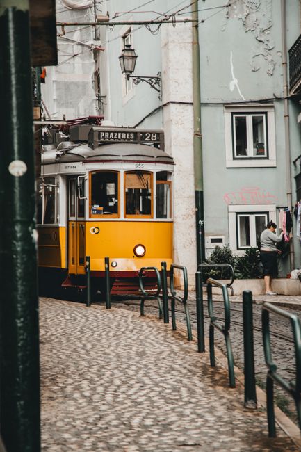 Capture of Lisbon's famous Tram 28 on a narrow cobblestone street, showcasing historic urban charm.