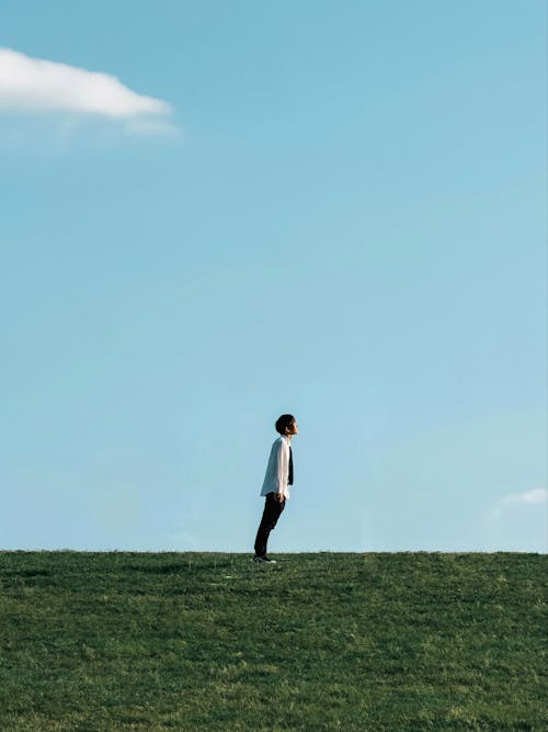 Man in Shirt Leaning on Grassland