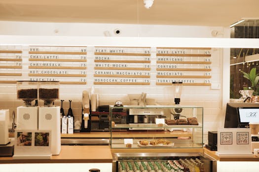 A modern coffee shop interior featuring a menu board and coffee bar setup in warm lighting.