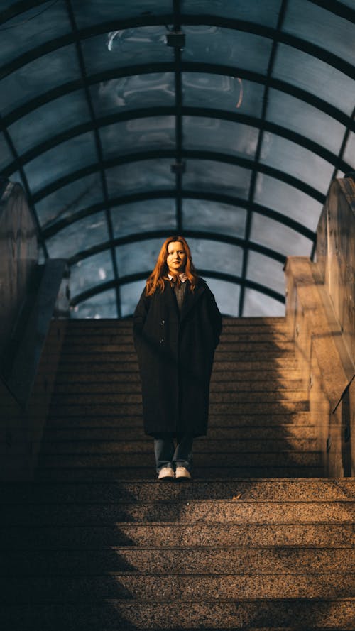 Woman in a Wide Woolen Coat on the Stairs