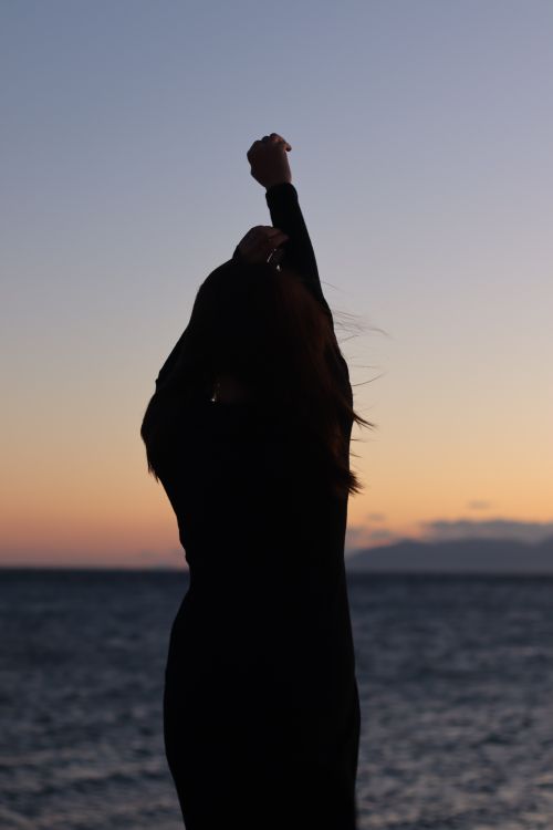Free Silhouette of a woman stretching by the sea at twilight, embodying relaxation and tranquility. Stock Photo