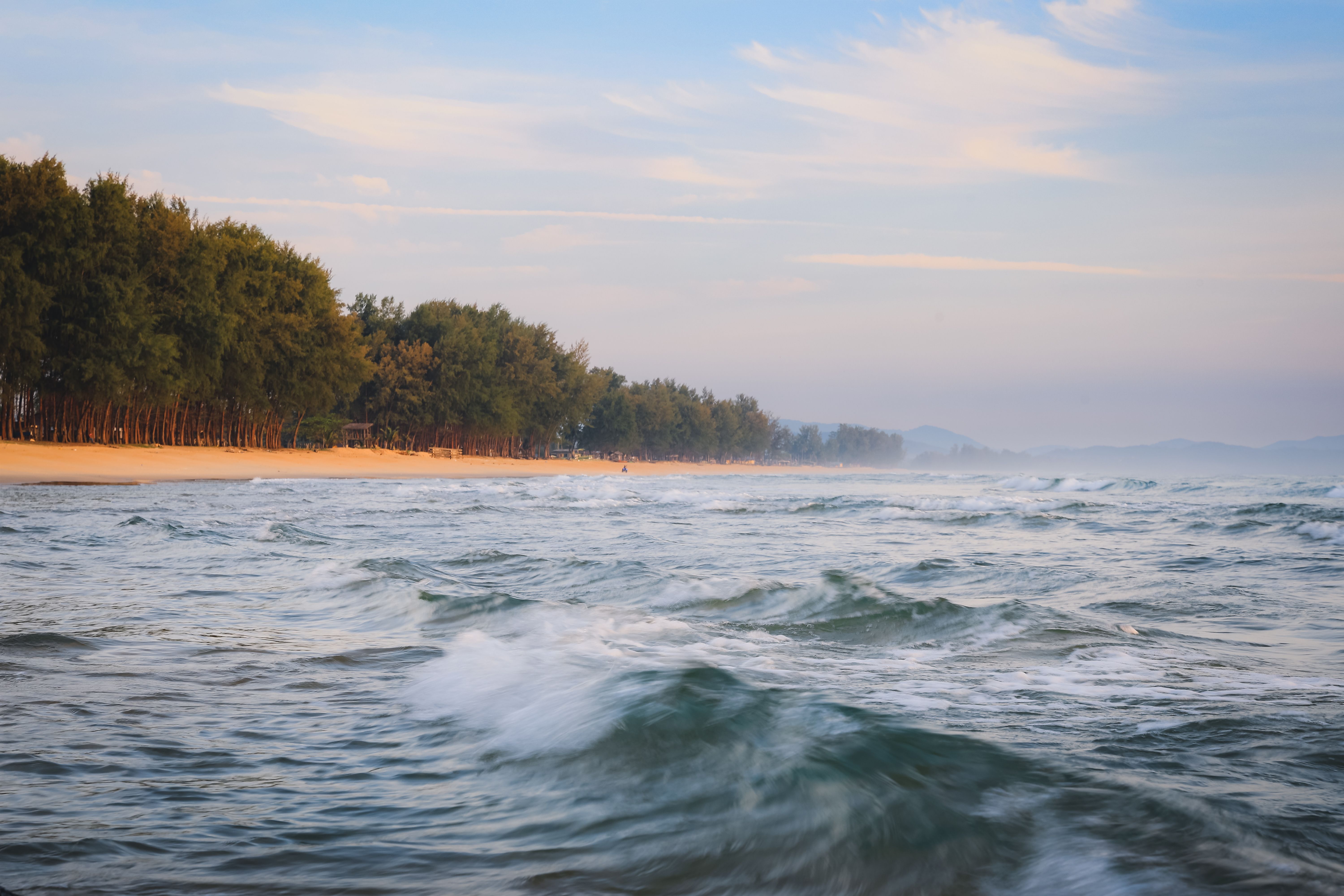 Tranquil waves at Kijal Beach with lush forest backdrop, Terengganu, Malaysia coast.