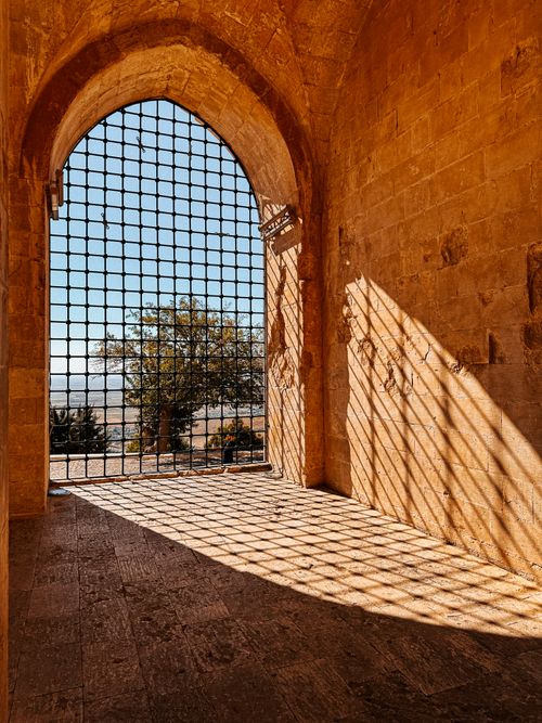 Free View of a historic stone gate in Mardin, Turkey with sunlight casting grid shadows. Perfect for travel and architecture themes. Stock Photo