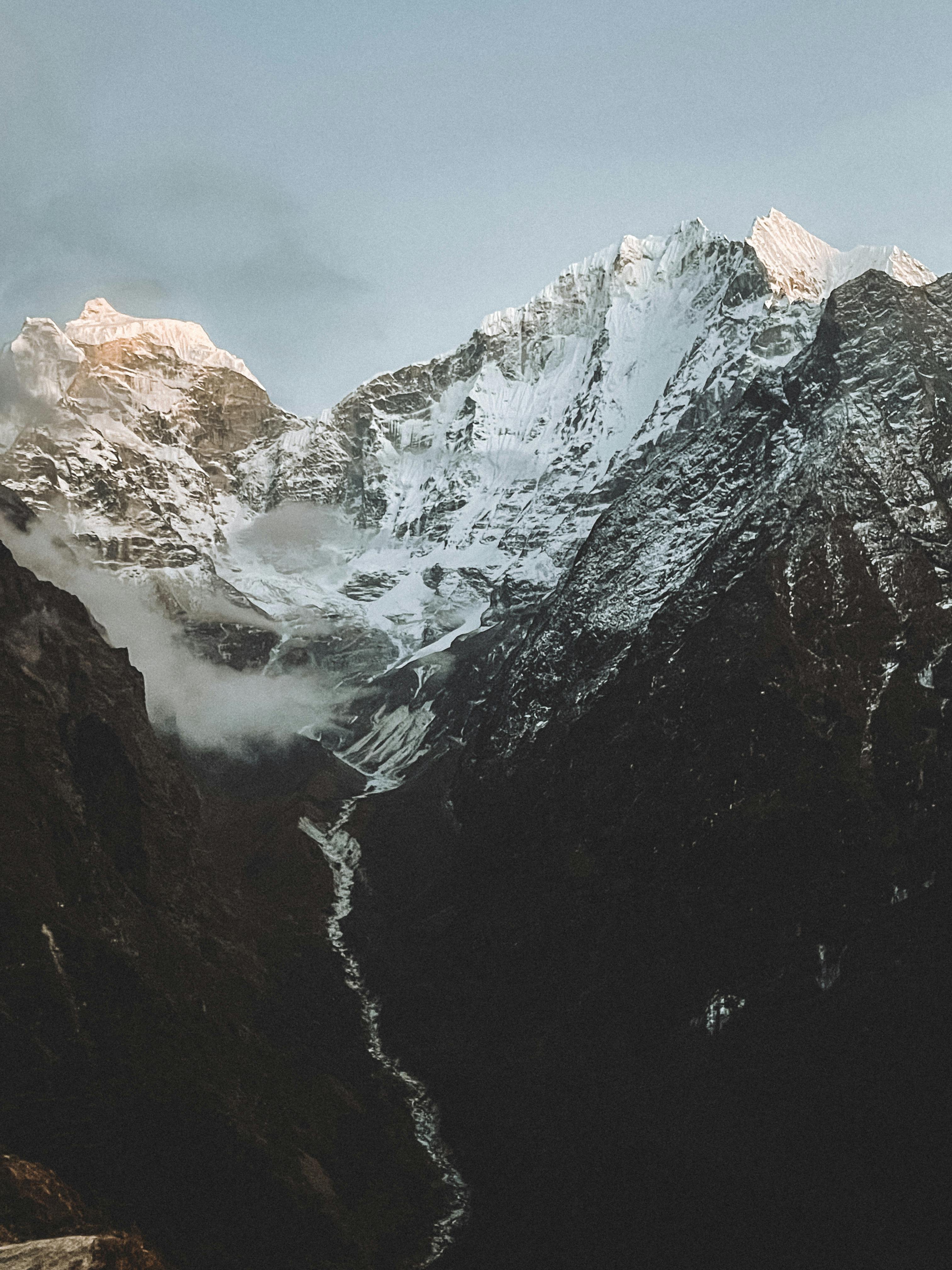 Breathtaking view of snowcapped mountains with a serene valley below, captured at sunrise.