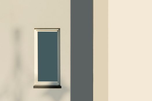 Sunlit window casting shadows on a minimalist modern building facade.