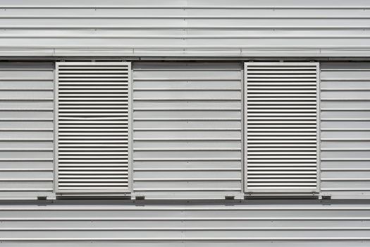 Close-up view of a modern industrial building exterior with louvered windows and metal panels.