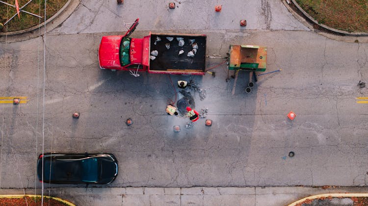 Aerial View Of Workers Digging Out A Manhole In The Street