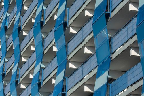 Free Detailed view of a modern building's facade with blue balconies showcasing urban architectural design. Stock Photo