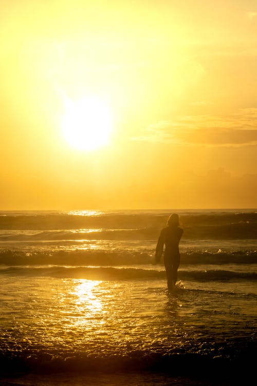 Sun over Surfer on Sea Shore at Sunset