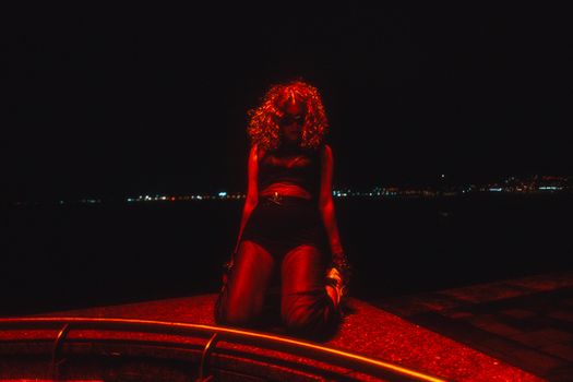 A captivating night scene featuring a person illuminated by dramatic red lighting, exuding mystery.
