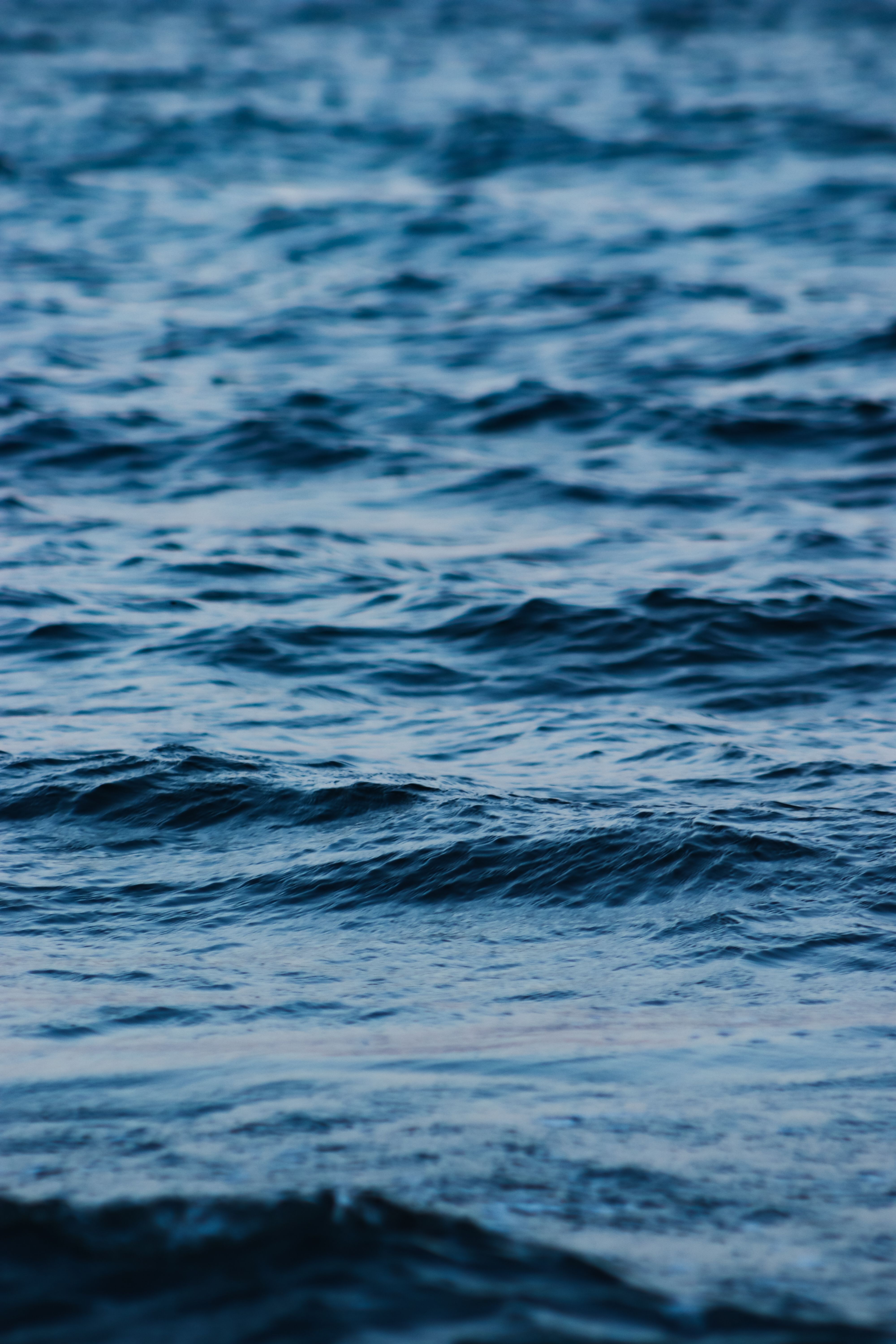 Tranquil blue ocean waves captured in a vertical frame with a focus on texture and color.