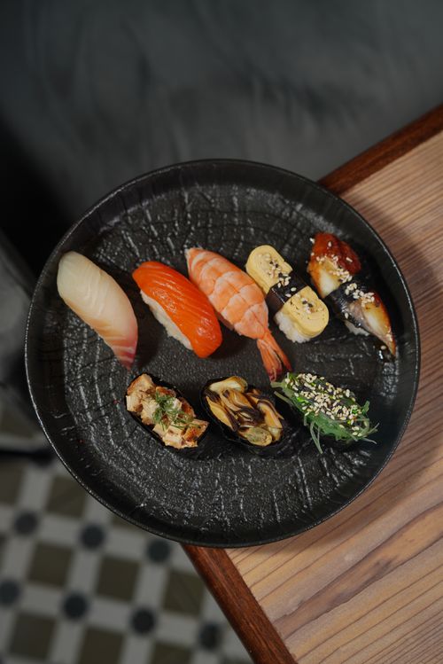 Free A black plate featuring a variety of sushi pieces elegantly arranged for a gourmet presentation. Stock Photo