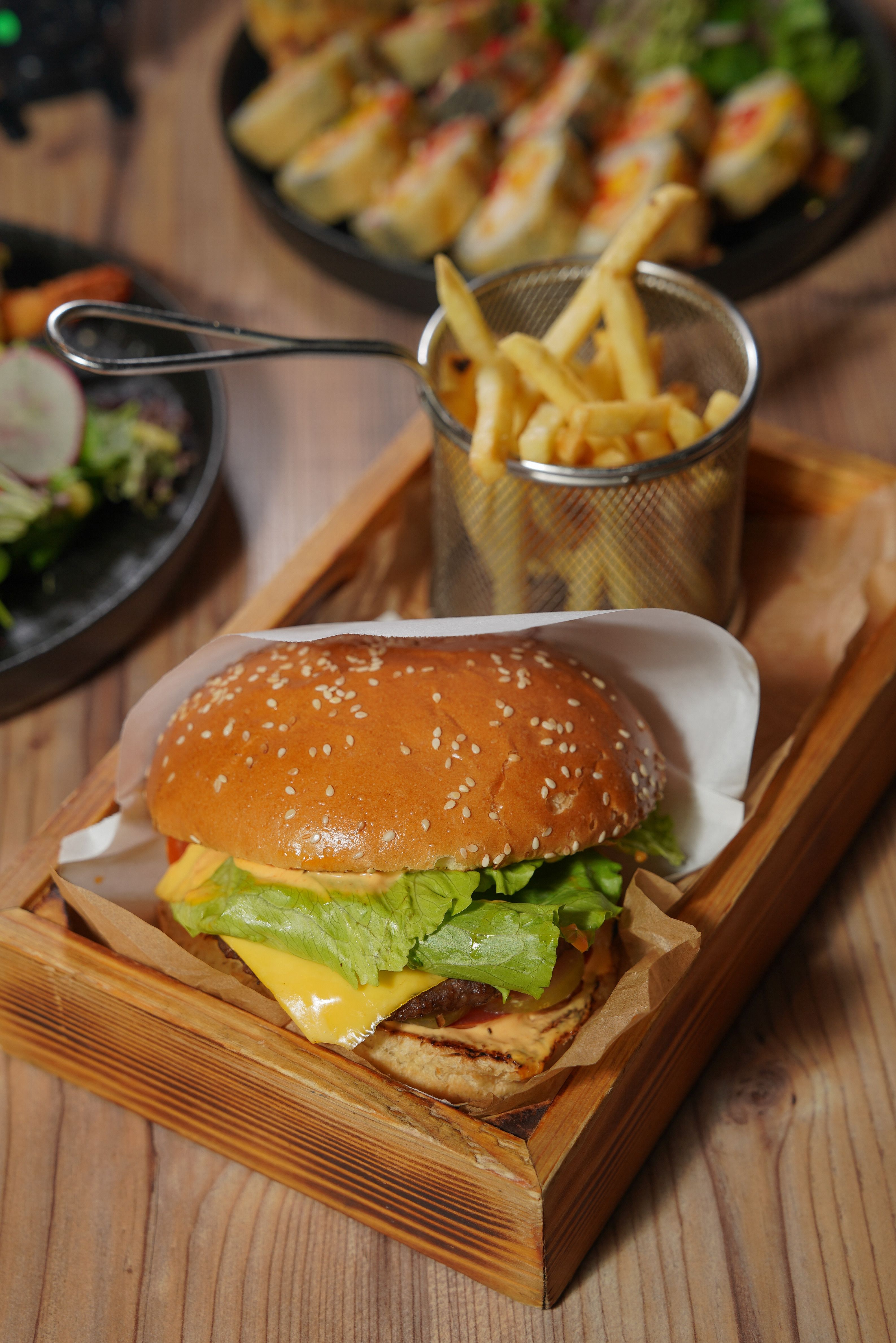 Appetizing cheeseburger with fresh fries served on a rustic wooden tray, perfect for food lovers.