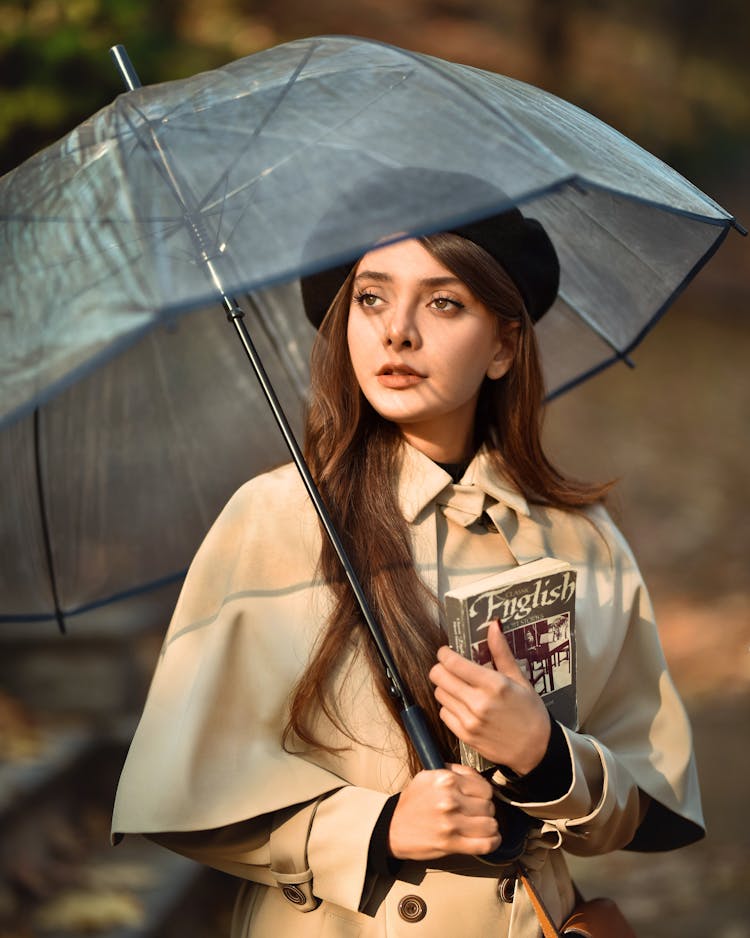 Young Woman Standing Outside With An Umbrella And A Book 