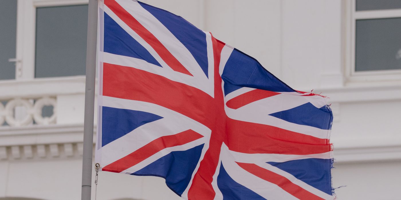 Close-up of the Union flag waving in front of a building in an urban area.