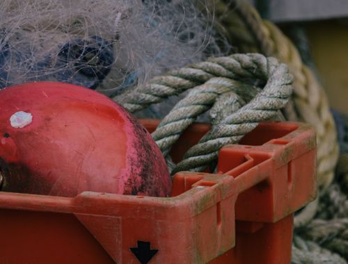Free A detailed photo of a red buoy and rope inside an orange bucket, ideal for maritime themes. Stock Photo