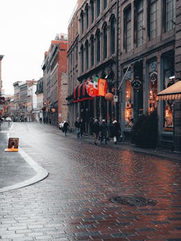 Charming urban scene of a wet street in Montreal with flags and passersby on a rainy day.