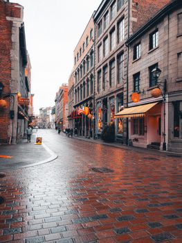 Charming view of Old Montreal's historic street with wet paving stones and classic facades.