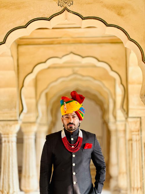 Free A model in traditional Indian attire with a turban, standing in an ornate arched corridor, exuding elegance. Stock Photo