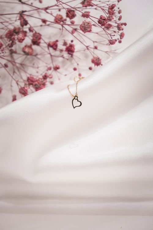 Free Heart pendant necklace on a delicate floral backdrop with soft white fabric. Stock Photo