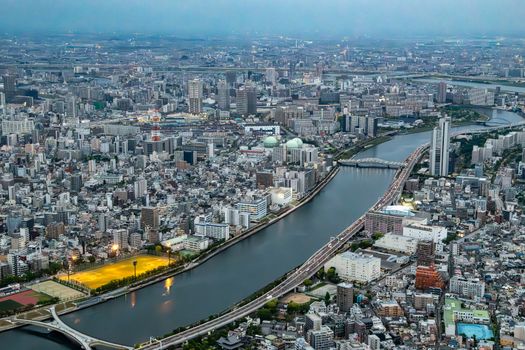 Aerial view of Tokyo's vibrant cityscape with river and skyscrapers at dusk.