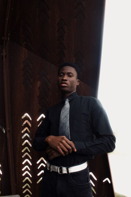 Elegant portrait of a man in black clothing with a fashionable tie, posing outdoors.