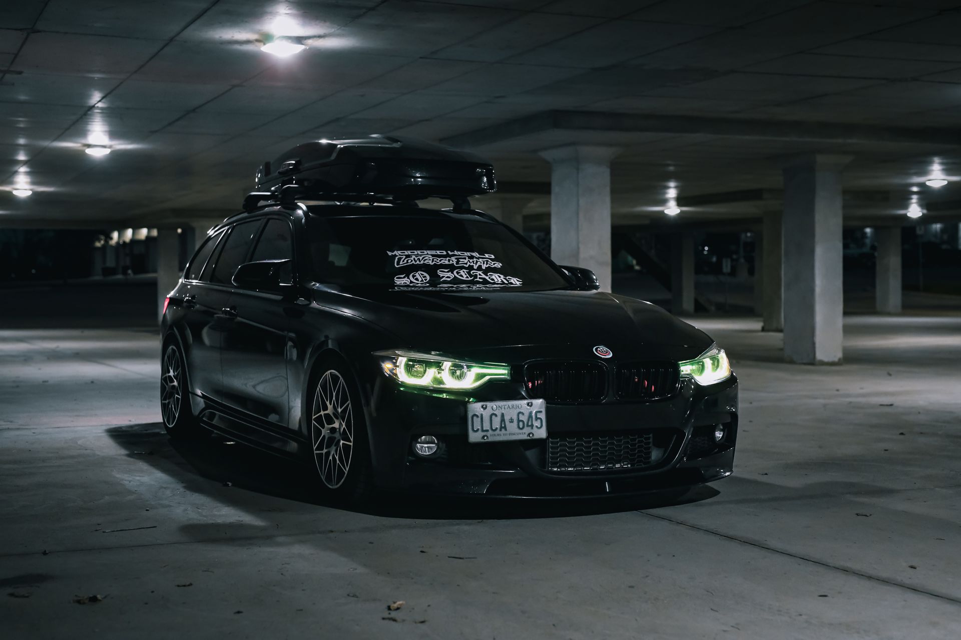 Black car with custom features parked in an underground garage at night.