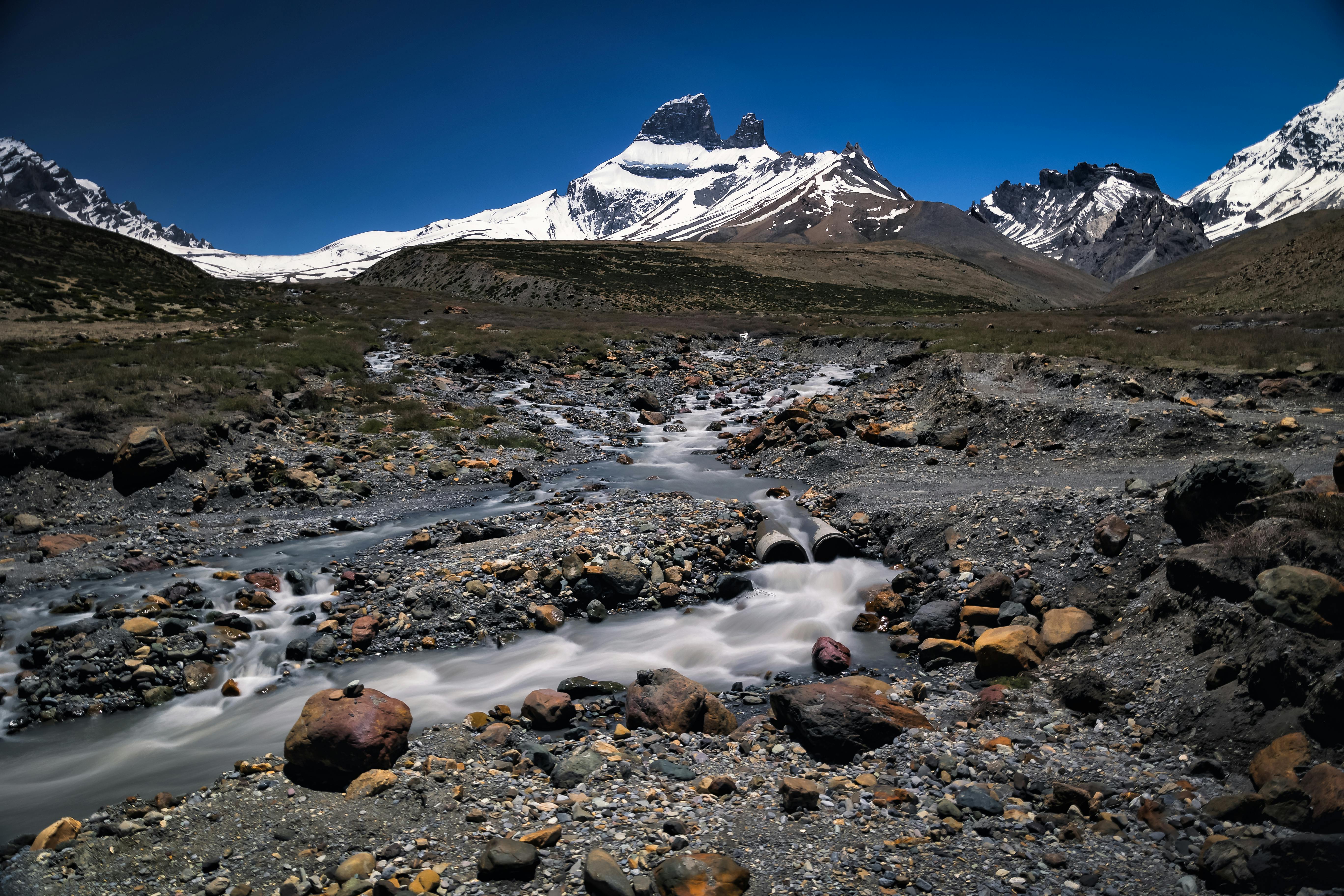 Panoramic view of the Leh mountains and a stream flowing through a rocky terrain under a starry night sky.