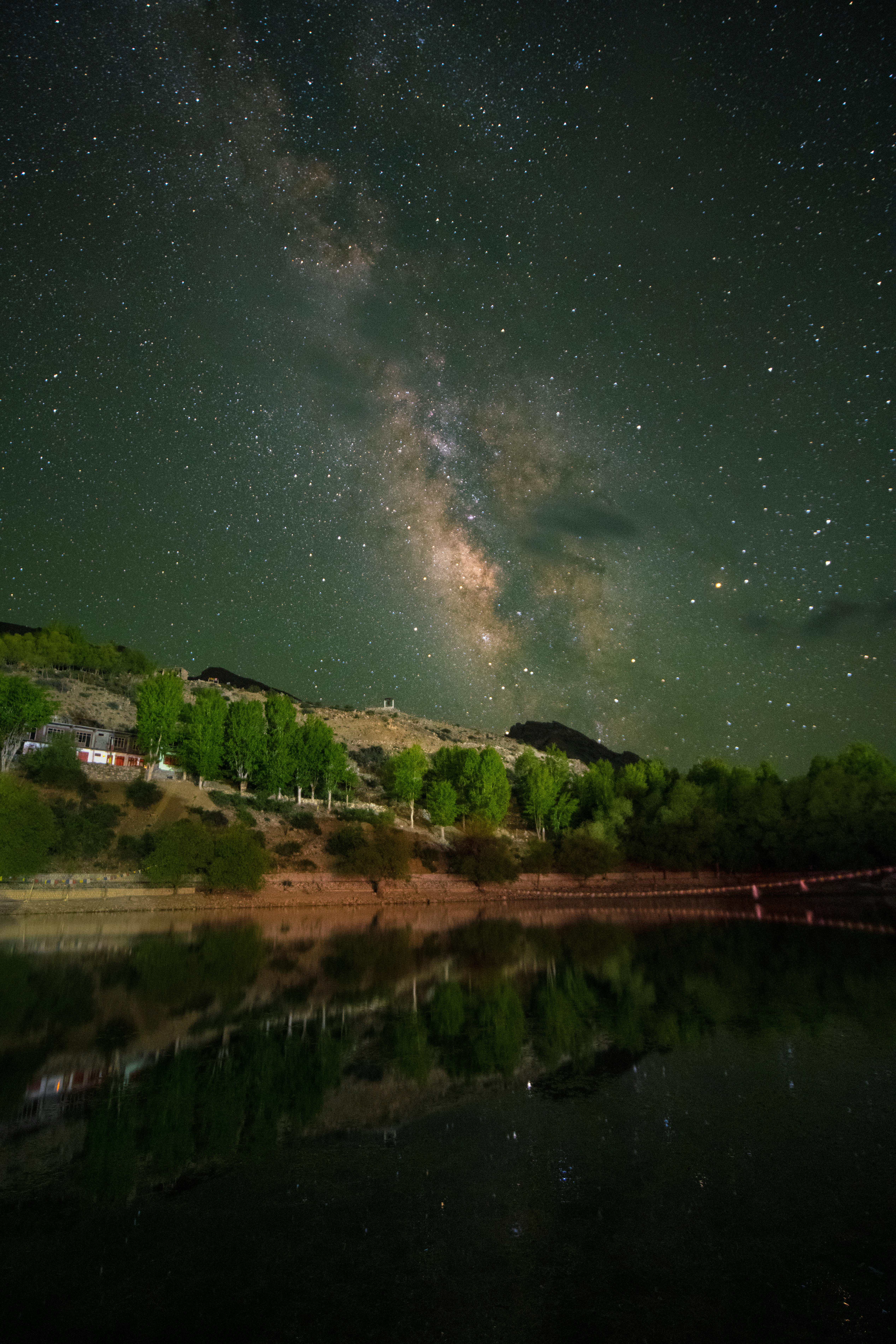 Milky Way over Himalayas reflecting in a serene lake in Kaza, India at night.