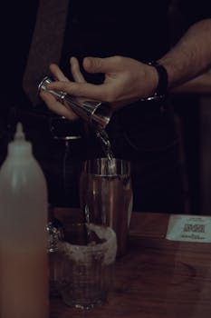 Close-up of a bartender pouring a drink into a cocktail shaker in an Istanbul bar.