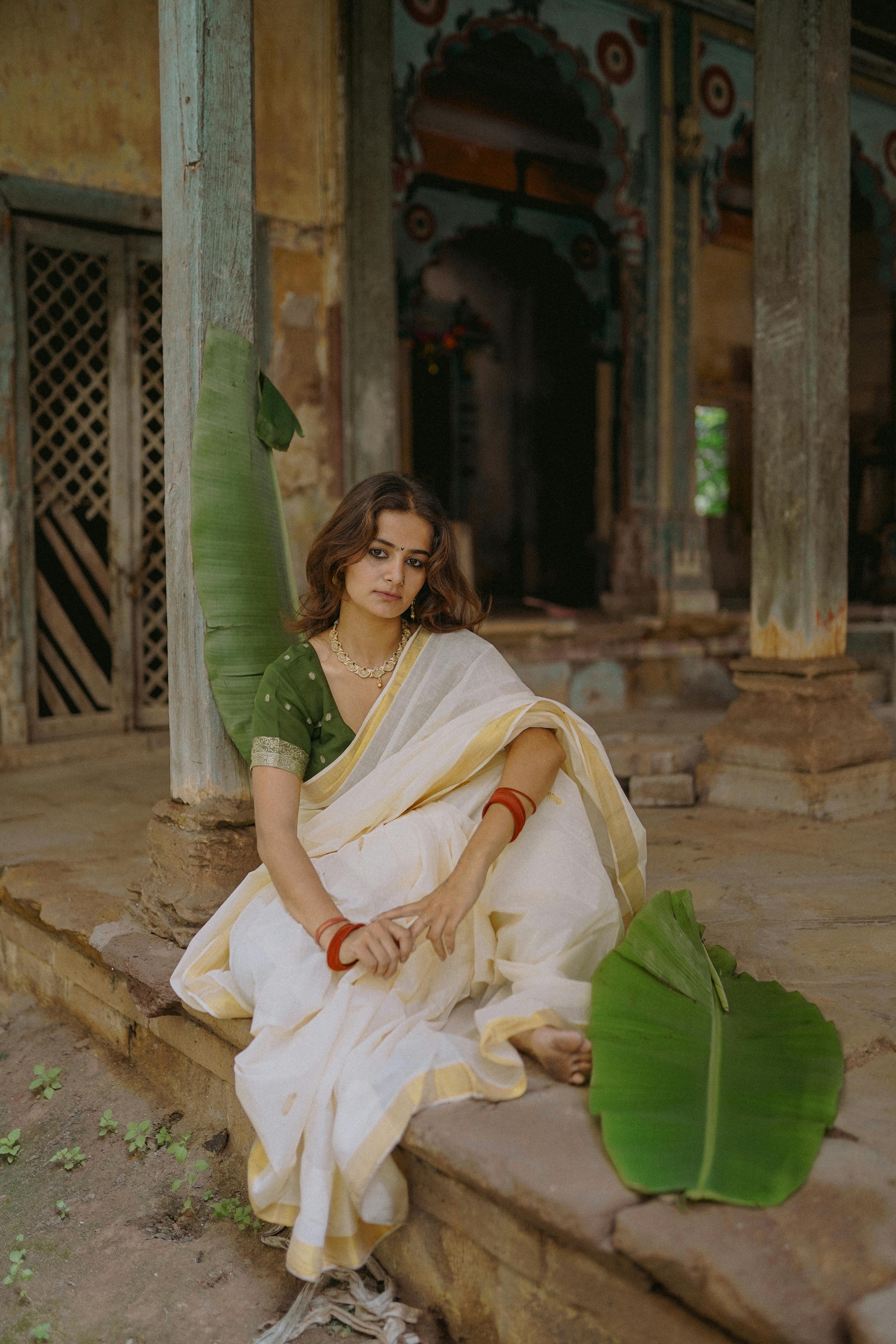 free photo of woman wearing a sari posing in a weathered traditional house