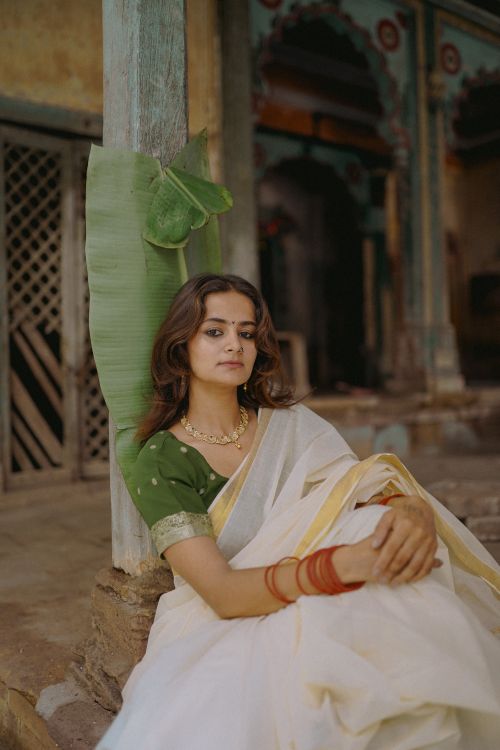 Free A woman in a traditional Indian sari is sitting gracefully indoors, exuding elegance and cultural richness. Stock Photo