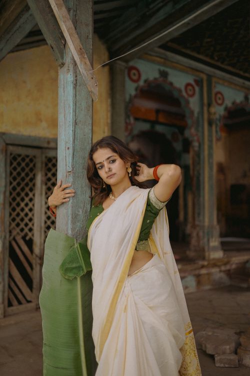Free Portrait of a woman in a sari, standing near a historic building facade, embodying cultural elegance. Stock Photo