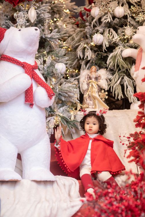 Free Adorable child in red cape amidst festive Christmas decorations with polar bears. Stock Photo