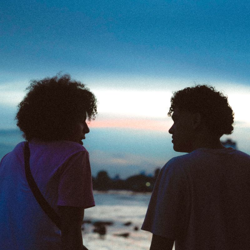 Two friends talking by the water at dusk, by Traveler stories photos on Pexels