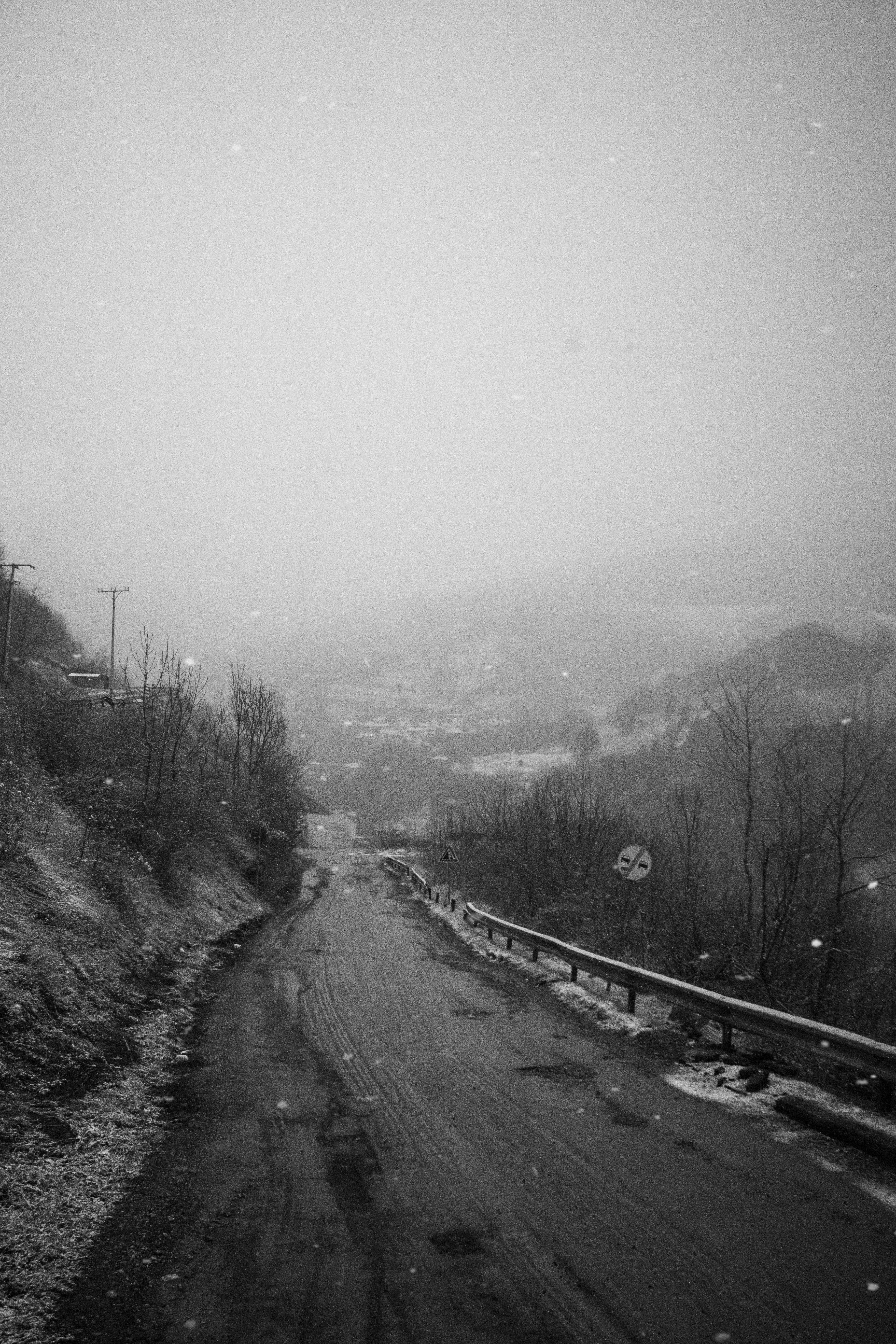 A foggy road in the mountains on a cold, snowy winter day.