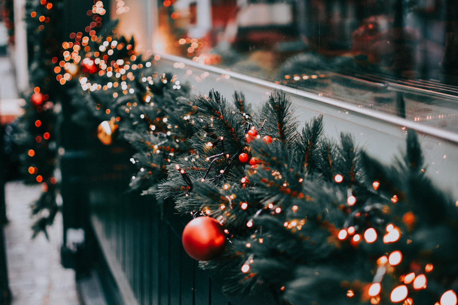 A window adorned with vibrant Christmas garland and warm glowing lights.