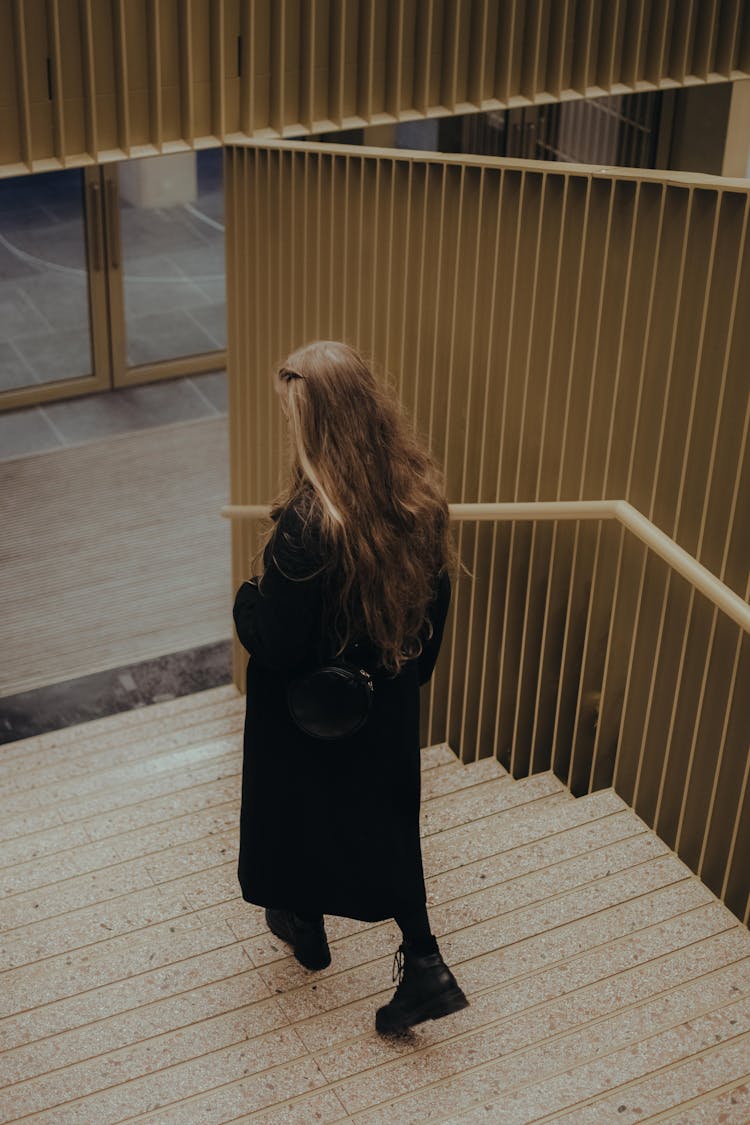 Back View Of A Woman Walking Down The Stairs 