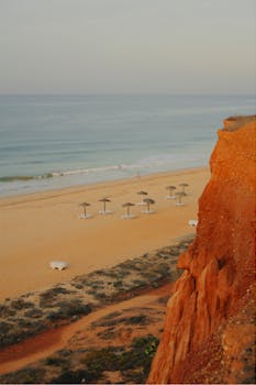 Explore the serene beauty of Algarve's coast with sandy shores and striking eroded cliffs at sunset.