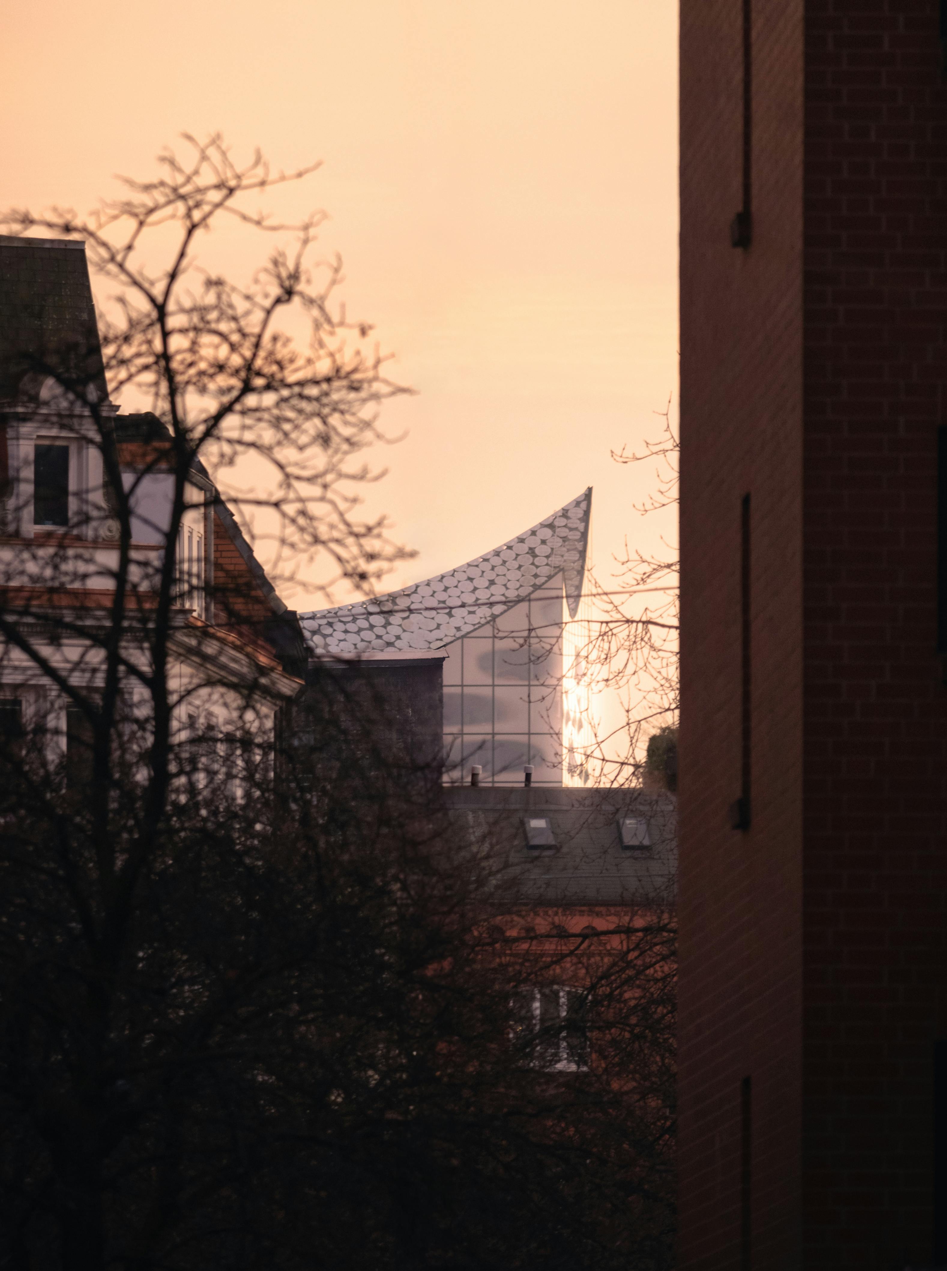 the sun is setting over a building with a large roof