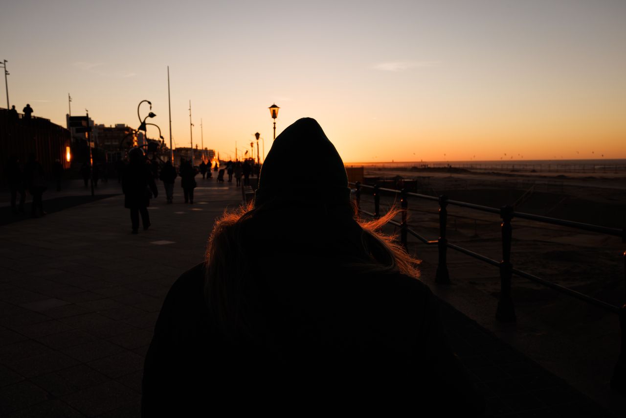 people walking along a promenade at sunset silhouetted against the sky