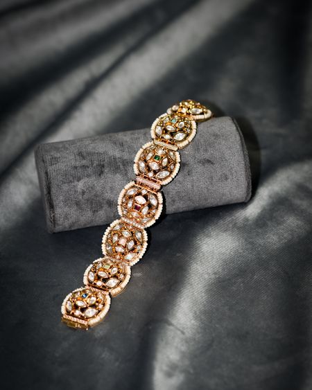 Golden floral kundan link bracelet on grey velvet