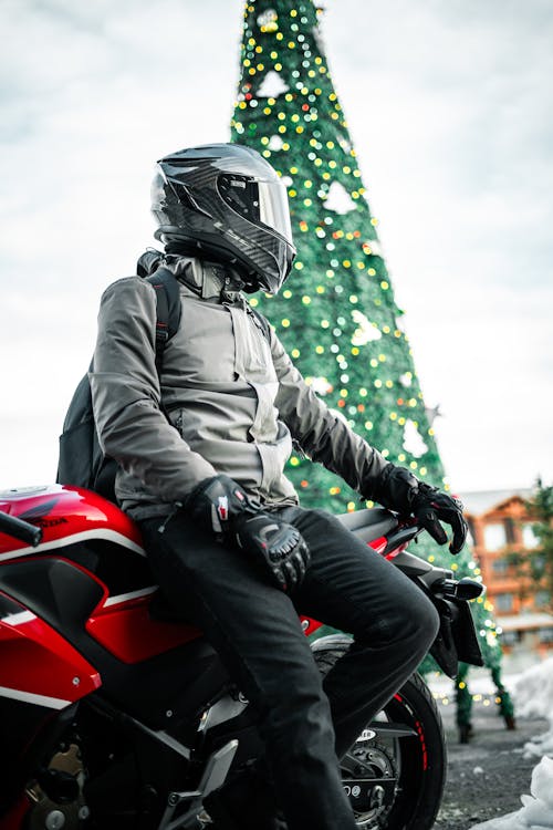 Man Leaning on a Motorcycle in front of a Christmas Tree 