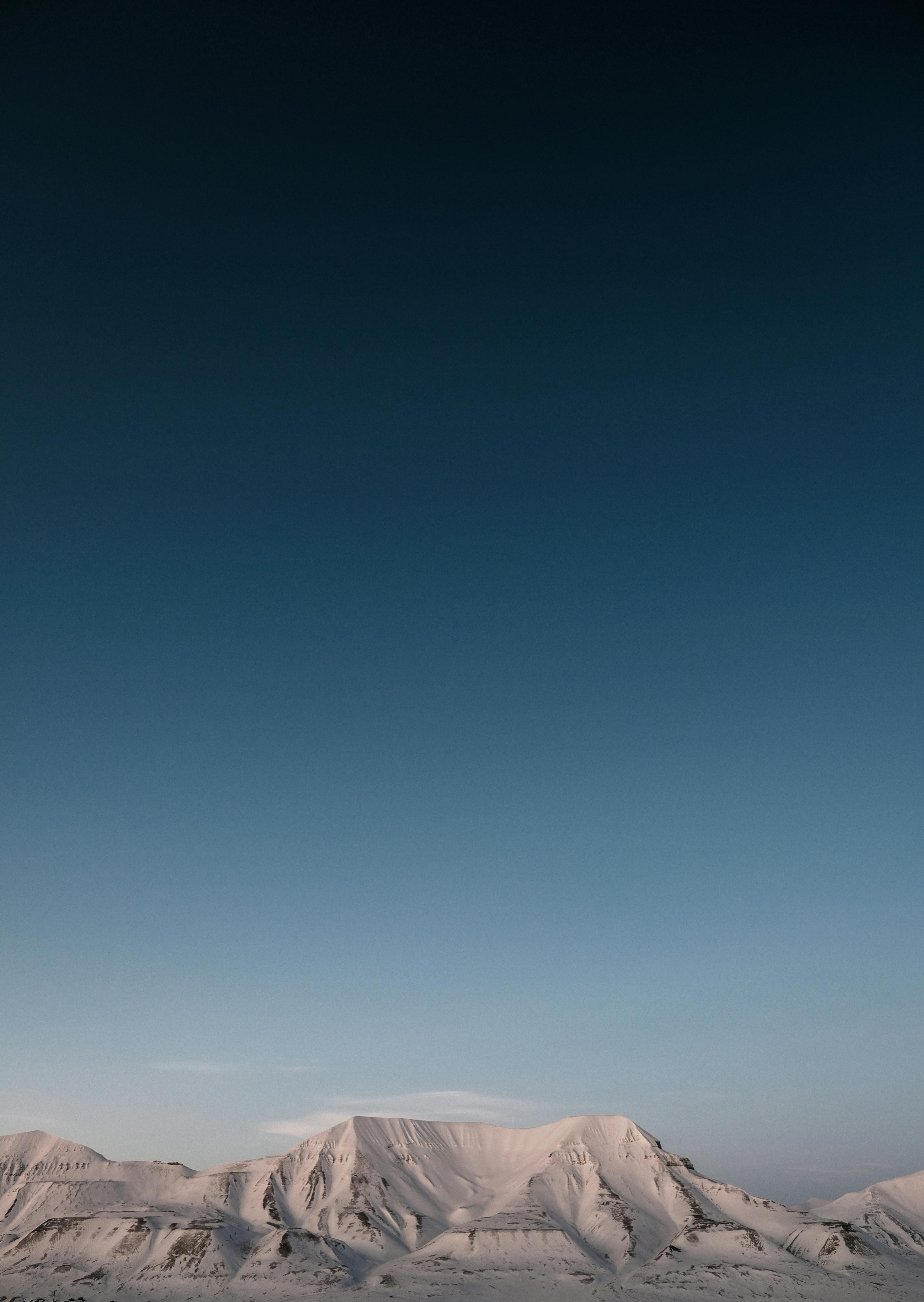 Captivating view of snow-covered mountains under a clear sky in Longyearbyen, Svalbard.