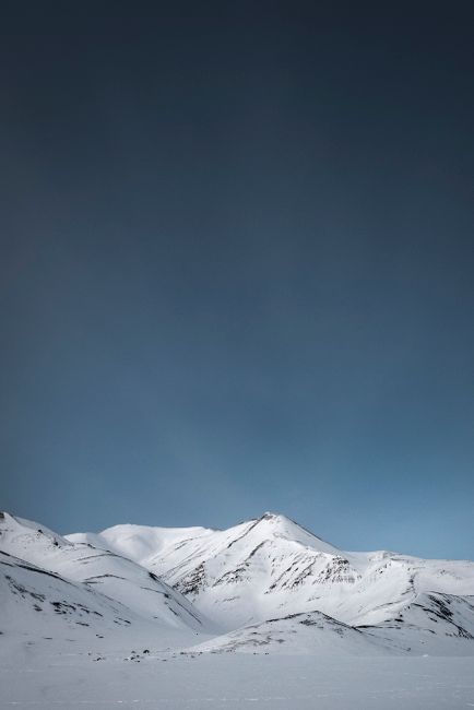 Crisp view of snowy mountains and clear sky in Longyearbyen, Svalbard, perfect for winter landscapes.