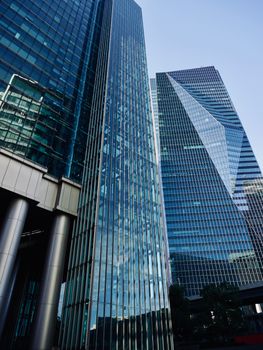 Tall modern skyscrapers with reflective glass facades in an urban downtown district.