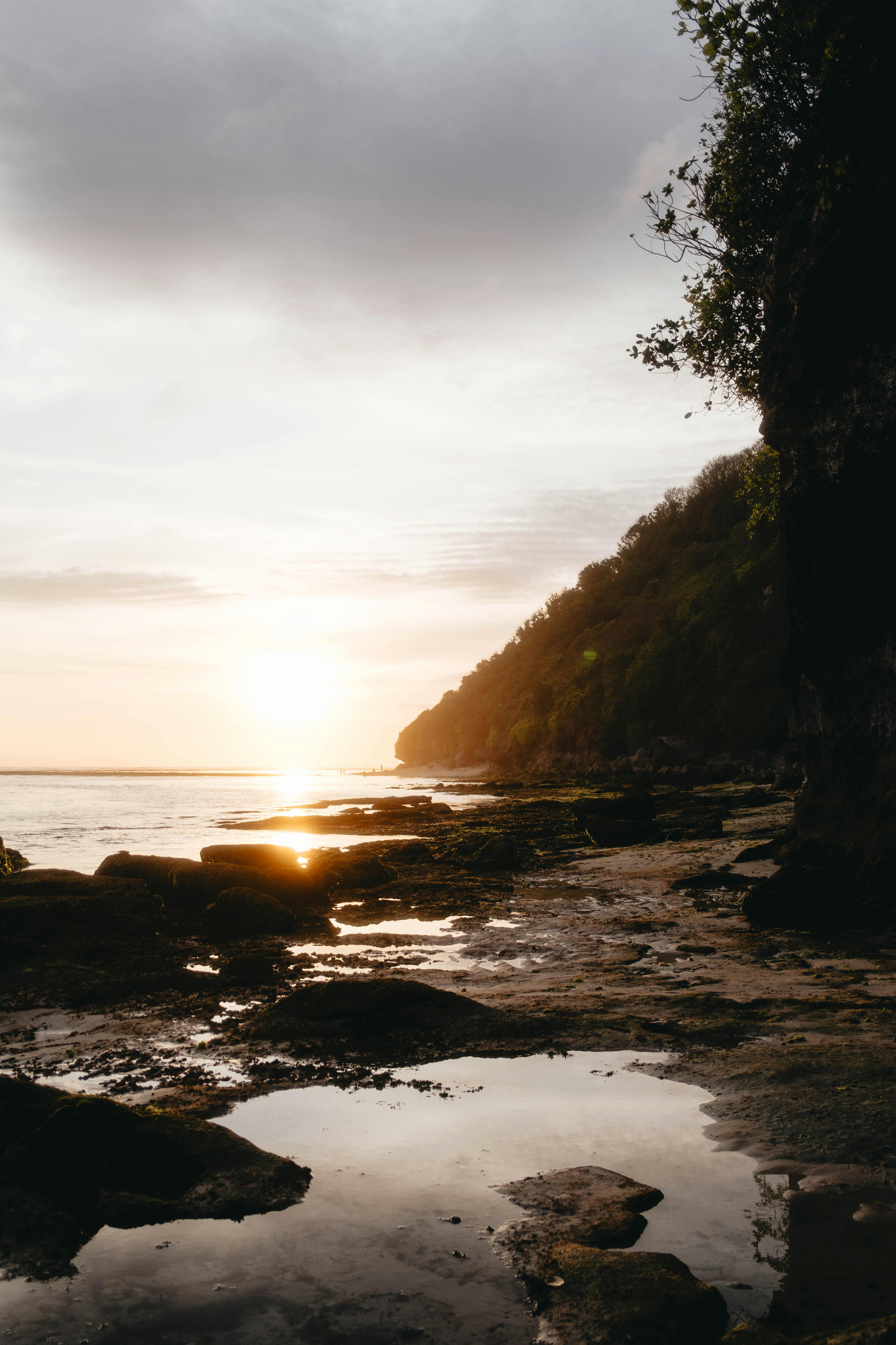 Serene rocky coastline at dawn capturing the glowing horizon and calm sea.