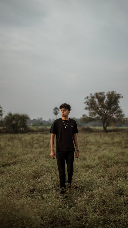 Man in Black Clothing Walking on a Meadow 