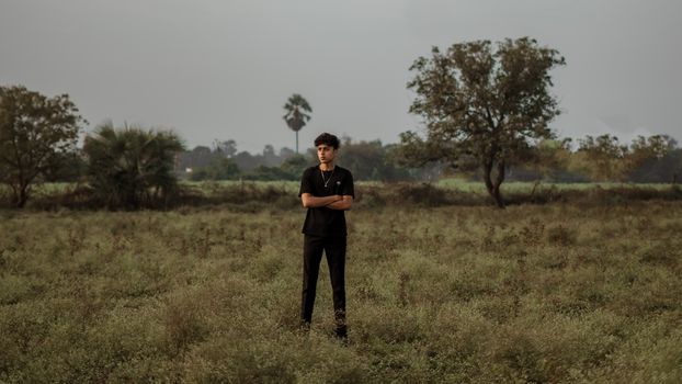A man standing in a field with a tree in the background